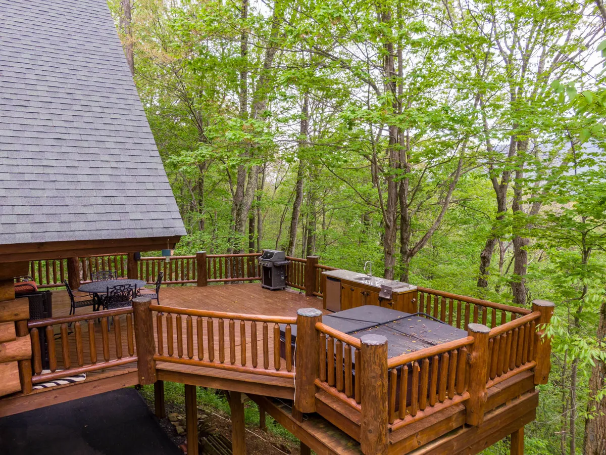 This exterior image showcases a wooden deck nestled among trees, featuring a grill and ample space for outdoor dining or casual lounging. The environment radiates warmth and is perfect for barbecuing, stargazing, or sipping morning coffee in nature.